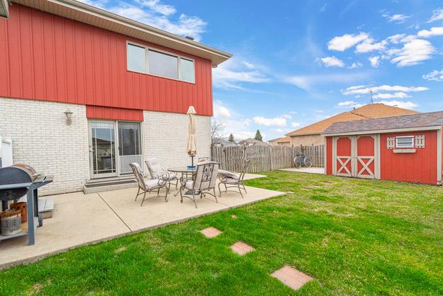 view of yard featuring a patio area, an outdoor structure, fence, and a storage unit