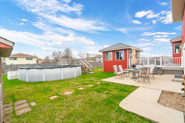 view of yard featuring a deck, a patio, an outdoor structure, fence, and a fenced in pool