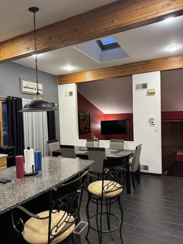 kitchen featuring dark stone counters, wood tiled floor, visible vents, and decorative light fixtures