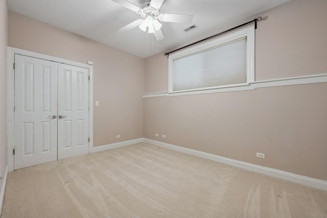 unfurnished bedroom featuring ceiling fan, light colored carpet, and a closet