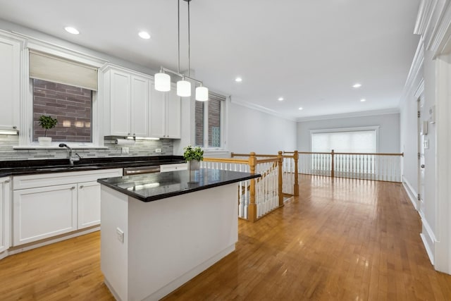 kitchen featuring hanging light fixtures, crown molding, a kitchen island, and white cabinets