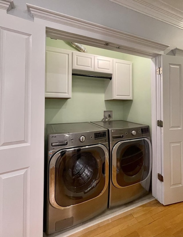 laundry area with cabinets, crown molding, light hardwood / wood-style flooring, and washer and dryer