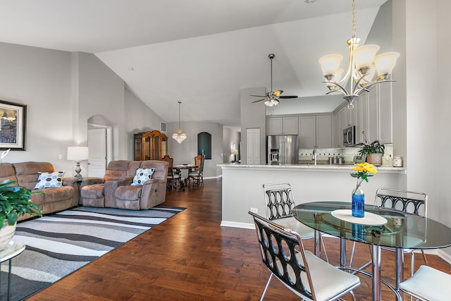 dining area with high vaulted ceiling, sink, ceiling fan with notable chandelier, and dark hardwood / wood-style flooring