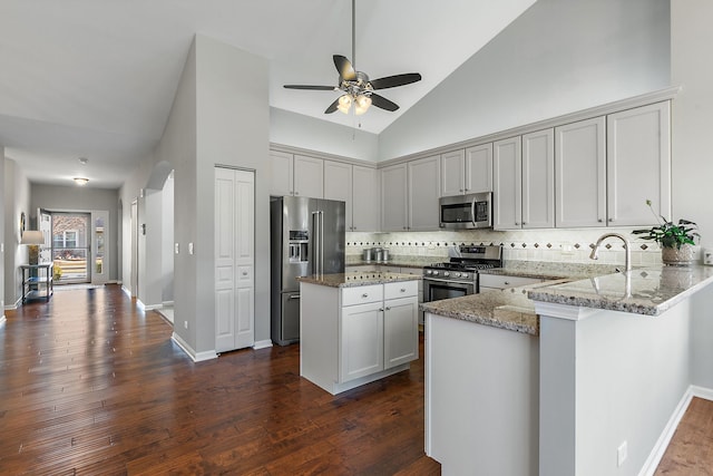 kitchen featuring a kitchen island, appliances with stainless steel finishes, light stone counters, and kitchen peninsula