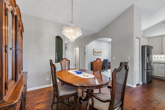 dining area with dark wood-type flooring, lofted ceiling, and an inviting chandelier