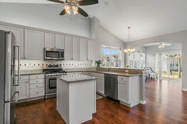 kitchen with sink, hanging light fixtures, kitchen peninsula, a kitchen island, and stainless steel appliances