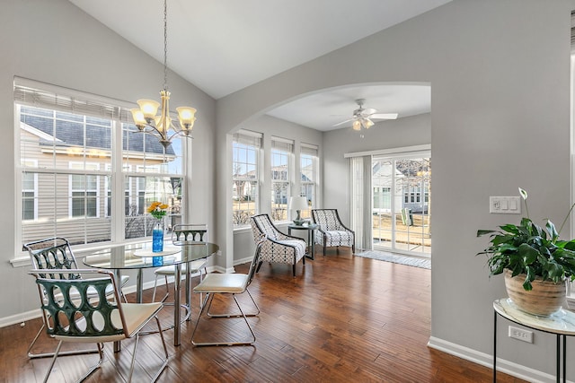 dining area featuring vaulted ceiling, dark wood-type flooring, and ceiling fan with notable chandelier