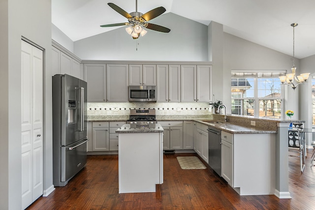 kitchen with sink, hanging light fixtures, kitchen peninsula, stone counters, and stainless steel appliances