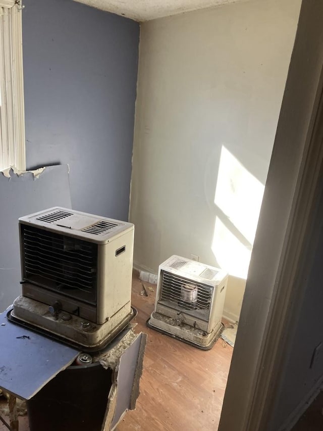 interior details featuring hardwood / wood-style flooring, heating unit, and a wall mounted AC