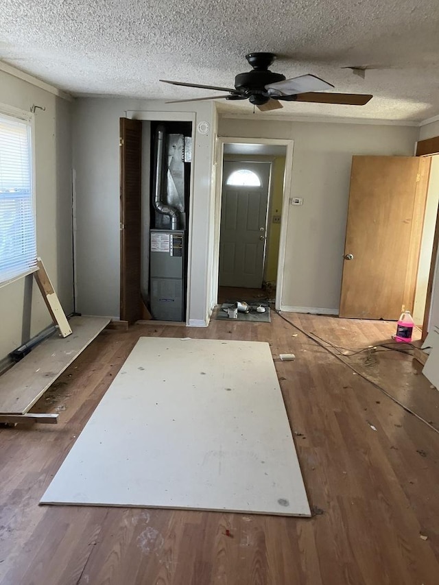 interior space with heating unit, ceiling fan, and a textured ceiling