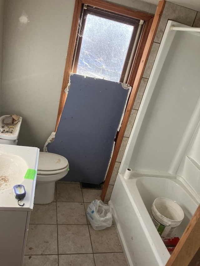 bathroom featuring a tub to relax in, vanity, toilet, and tile patterned flooring