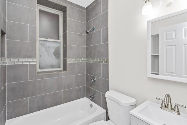 full bathroom featuring tiled shower / bath, vanity, and toilet