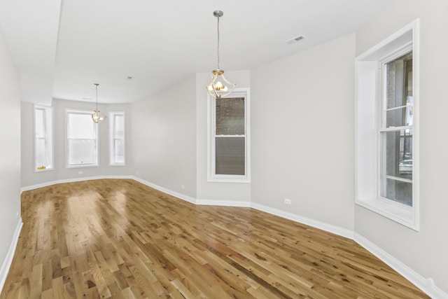 unfurnished room featuring an inviting chandelier and hardwood / wood-style floors