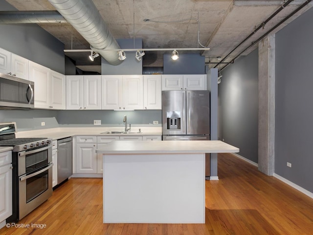 kitchen featuring stainless steel appliances, a kitchen island, sink, and white cabinets