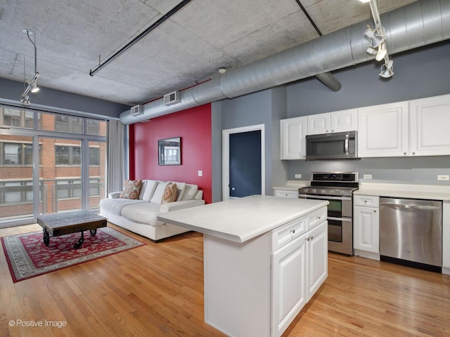 kitchen with a kitchen island, white cabinetry, appliances with stainless steel finishes, and light wood-type flooring