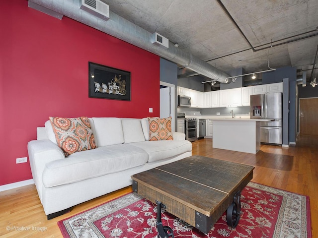 living room featuring sink and light hardwood / wood-style flooring