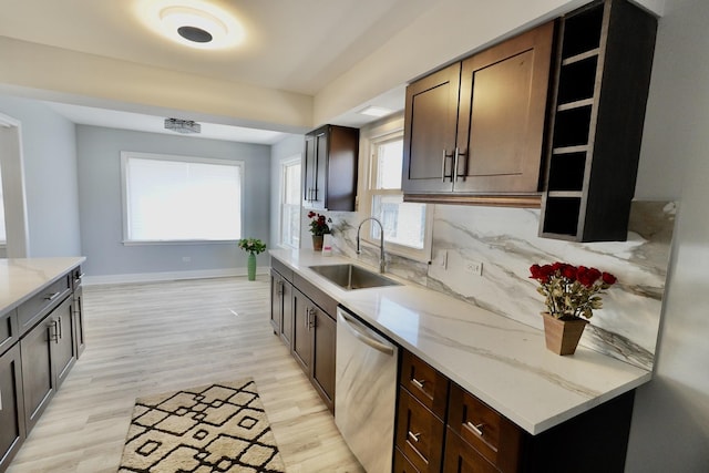 kitchen with sink, backsplash, stainless steel dishwasher, light stone counters, and light hardwood / wood-style flooring