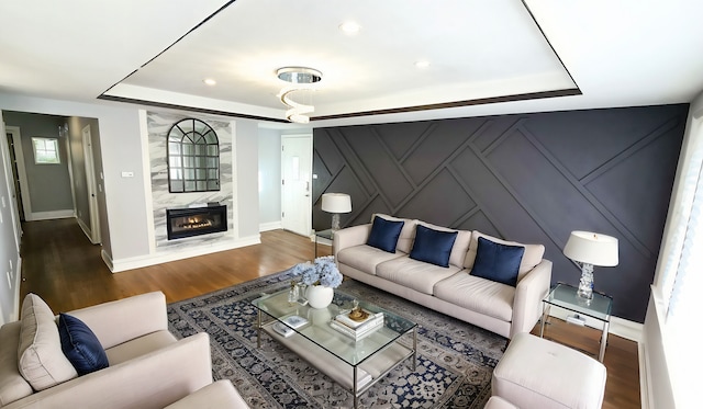 living room featuring a premium fireplace, a tray ceiling, and dark hardwood / wood-style floors