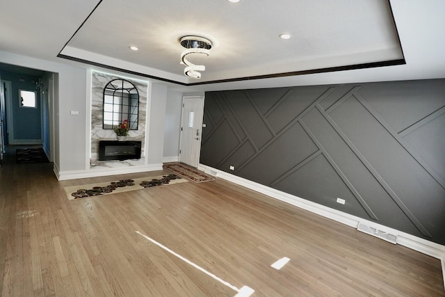 foyer with hardwood / wood-style flooring, a premium fireplace, and a tray ceiling