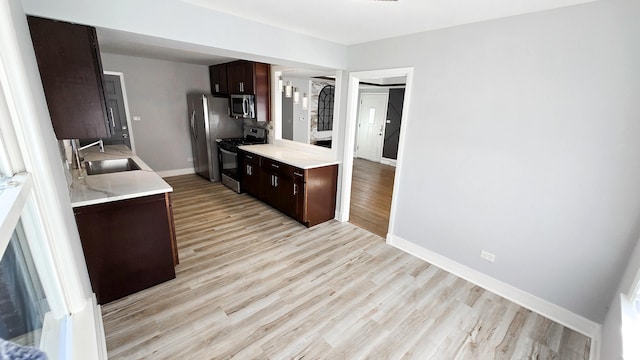 kitchen with sink, dark brown cabinets, light hardwood / wood-style floors, and appliances with stainless steel finishes