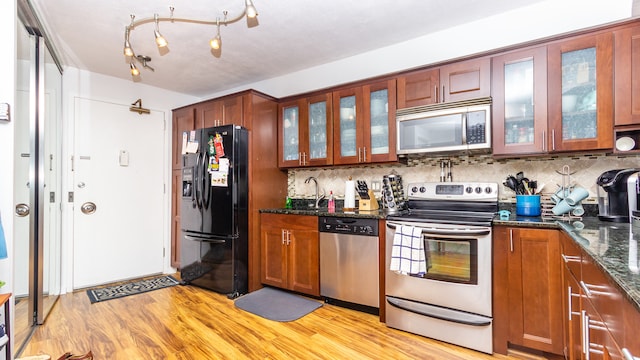 300 N State St Unit 2830, Chicago, IL 60654 - kitchen with appliances with stainless steel finishes, light wood-style floors, tasteful backsplash, and dark stone countertops
