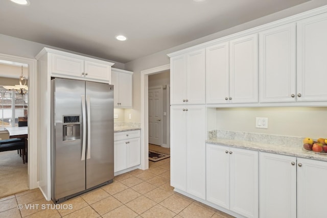 kitchen featuring white cabinets, light tile patterned floors, a notable chandelier, stainless steel fridge with ice dispenser, and light stone countertops