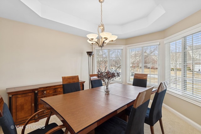 carpeted dining area with a notable chandelier, a tray ceiling, and a wealth of natural light