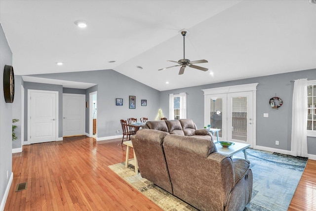 living area with baseboards, visible vents, lofted ceiling, light wood-style flooring, and ceiling fan