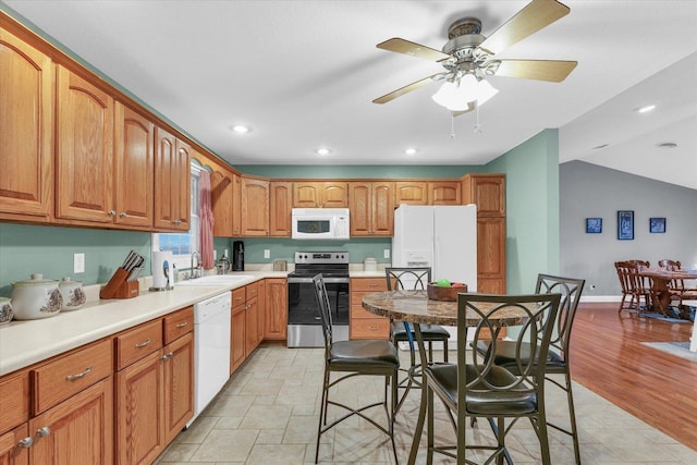 kitchen featuring ceiling fan, light countertops, brown cabinetry, white appliances, and a sink