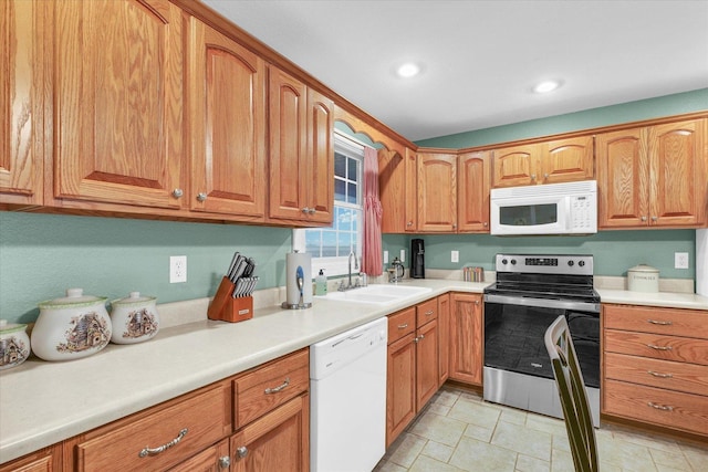 kitchen featuring white appliances, brown cabinets, and a sink