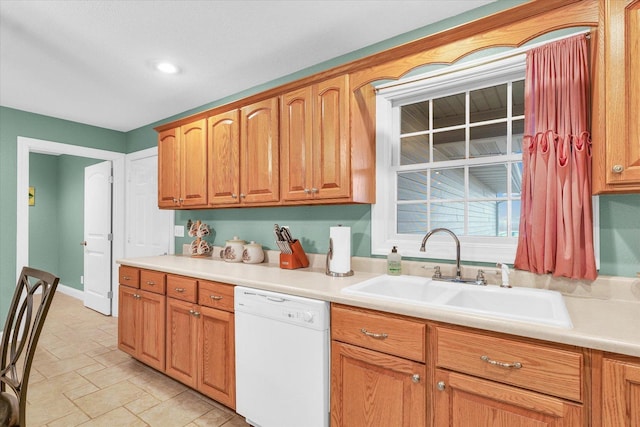 kitchen with brown cabinetry, dishwasher, light countertops, and a sink