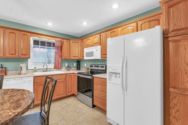 kitchen featuring a sink, stone finish flooring, recessed lighting, white appliances, and light countertops