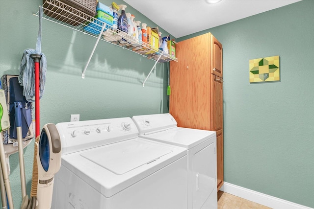 clothes washing area featuring light tile patterned flooring, cabinet space, baseboards, and washer and clothes dryer