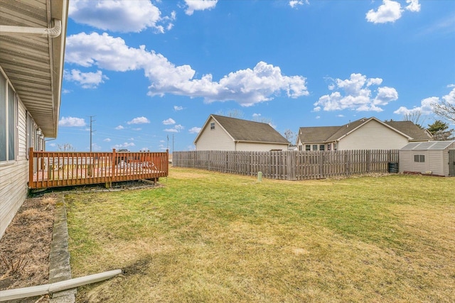 view of yard with a deck, an outdoor structure, a storage unit, and a fenced backyard