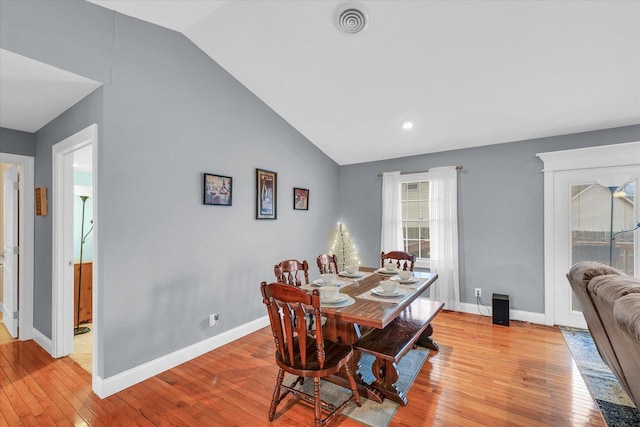 dining area featuring lofted ceiling, light wood-style flooring, visible vents, and baseboards