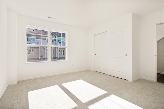 unfurnished bedroom with light carpet and a closet