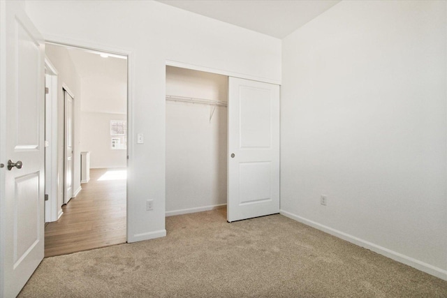 unfurnished bedroom with light colored carpet and a closet