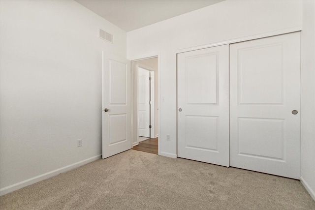 unfurnished bedroom featuring light colored carpet and a closet