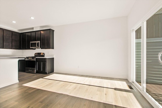 kitchen with dark brown cabinetry, stainless steel appliances, and light hardwood / wood-style floors