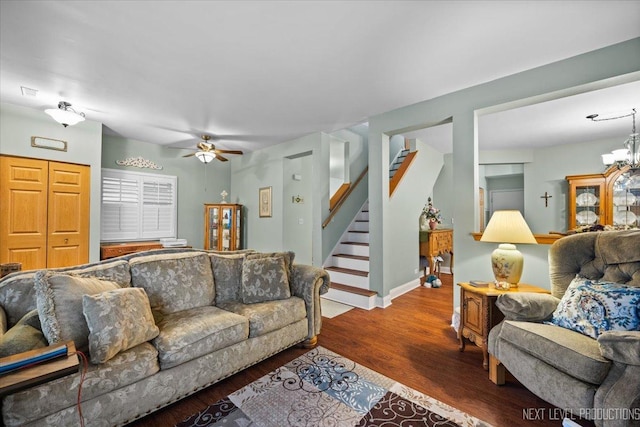 living room featuring ceiling fan with notable chandelier and dark wood-type flooring