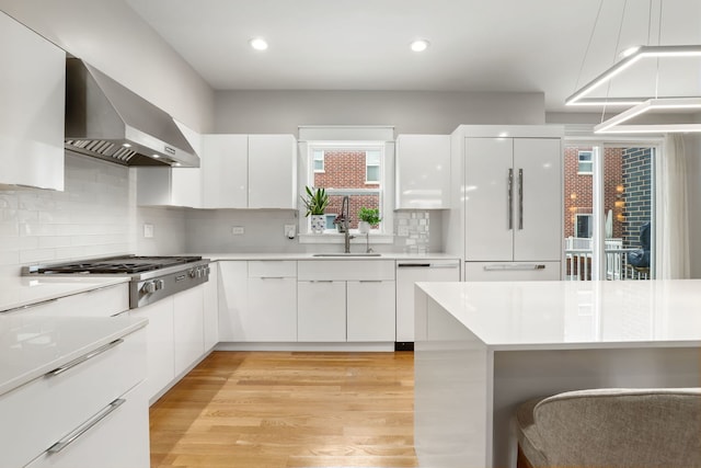 kitchen with white cabinetry, wall chimney exhaust hood, built in refrigerator, and dishwasher