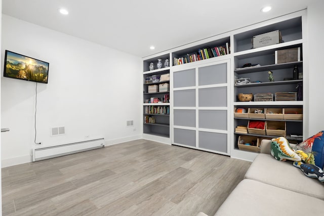 unfurnished room featuring a baseboard radiator, light hardwood / wood-style floors, and built in shelves