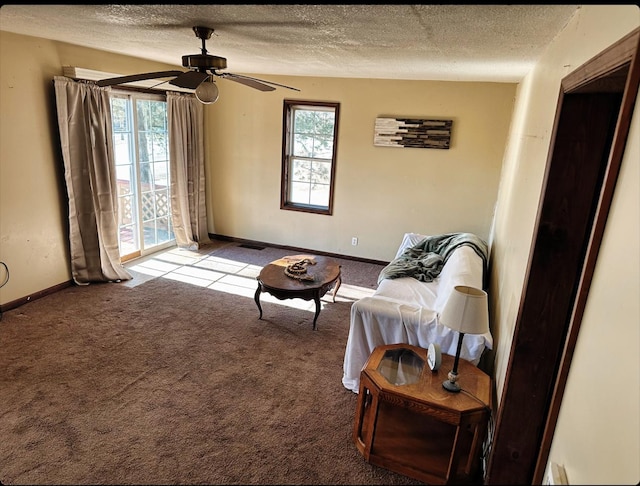 carpeted living room featuring ceiling fan and a textured ceiling