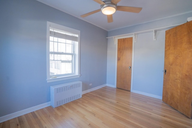 unfurnished bedroom with crown molding, radiator heating unit, a closet, ceiling fan, and light hardwood / wood-style floors