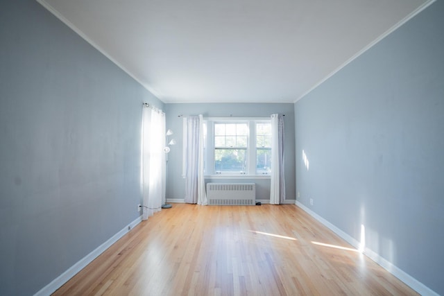 spare room featuring ornamental molding, radiator heating unit, and light hardwood / wood-style floors