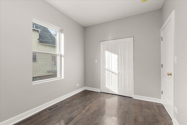 unfurnished bedroom with dark hardwood / wood-style floors and a closet