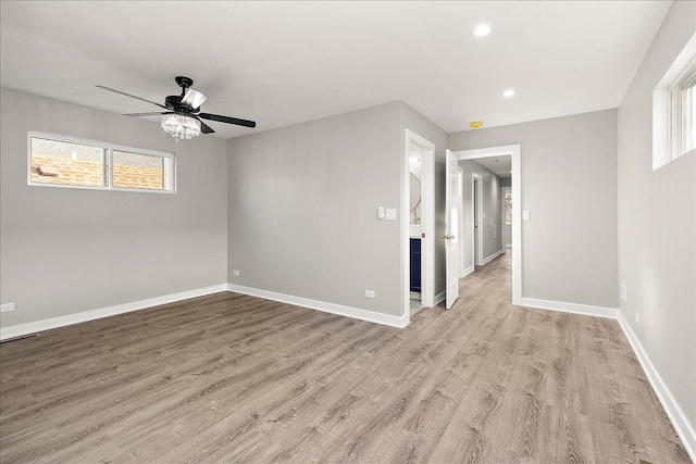 empty room featuring ceiling fan, a wealth of natural light, and light wood-type flooring