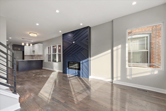 unfurnished living room featuring dark wood-type flooring and sink