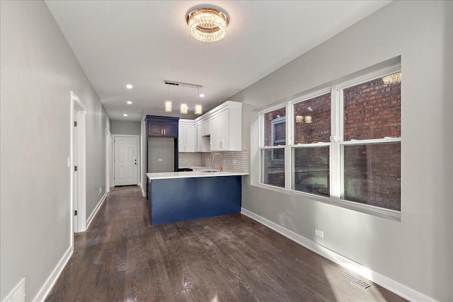 kitchen with sink, white cabinetry, tasteful backsplash, hanging light fixtures, and kitchen peninsula