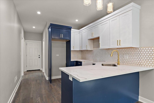 kitchen with tasteful backsplash, white cabinetry, sink, and decorative light fixtures